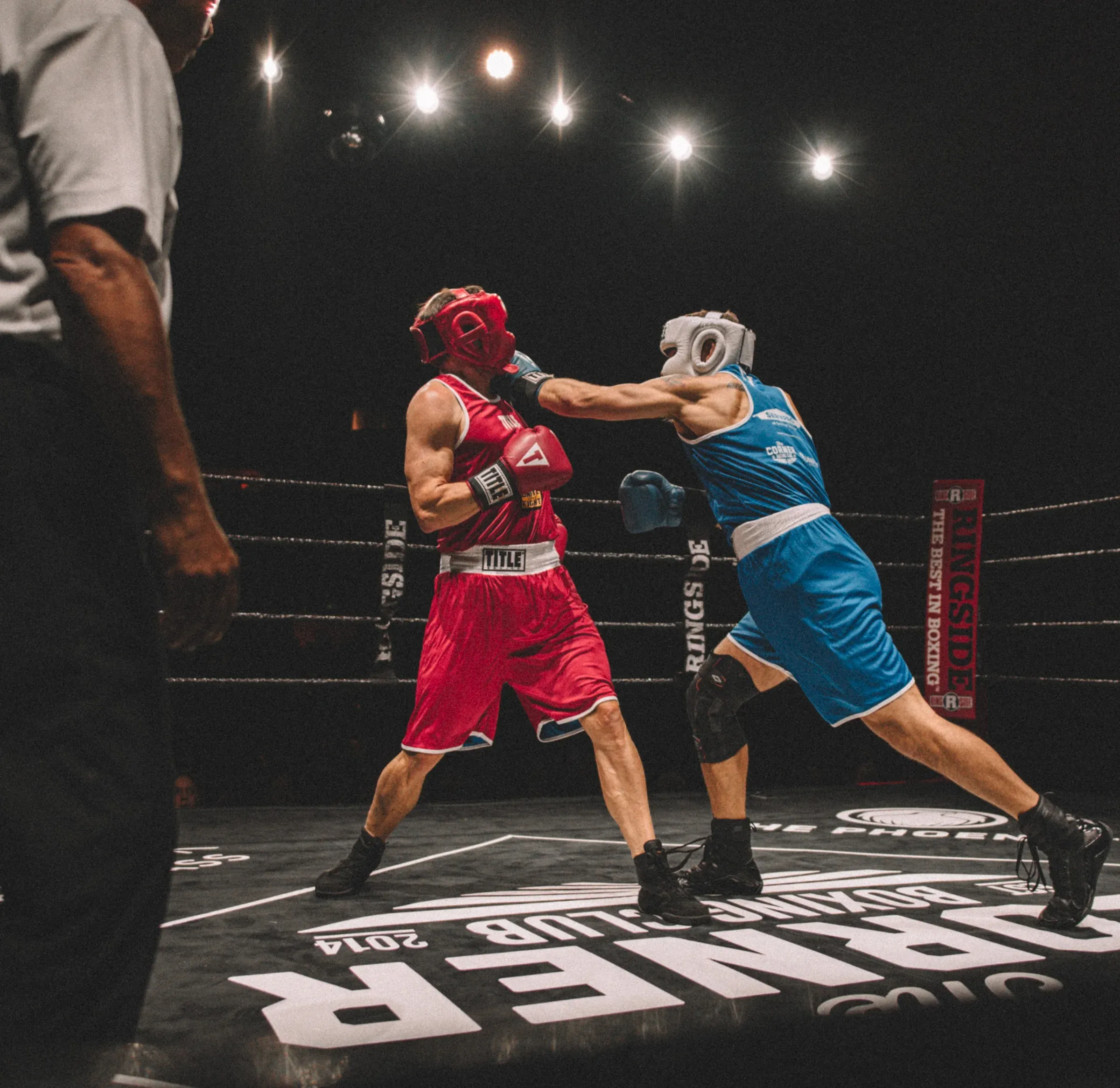 Two boxers trading punches in the ring at a Corner Boxing Club fight night